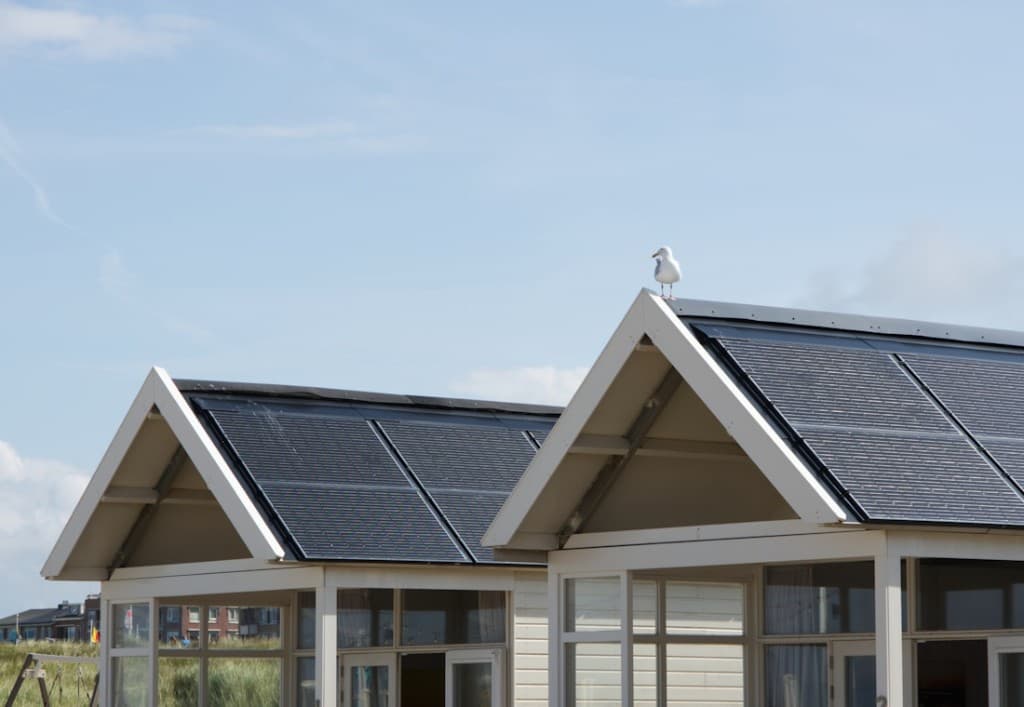 White cabin roofs covered in solar panels against a clear sky